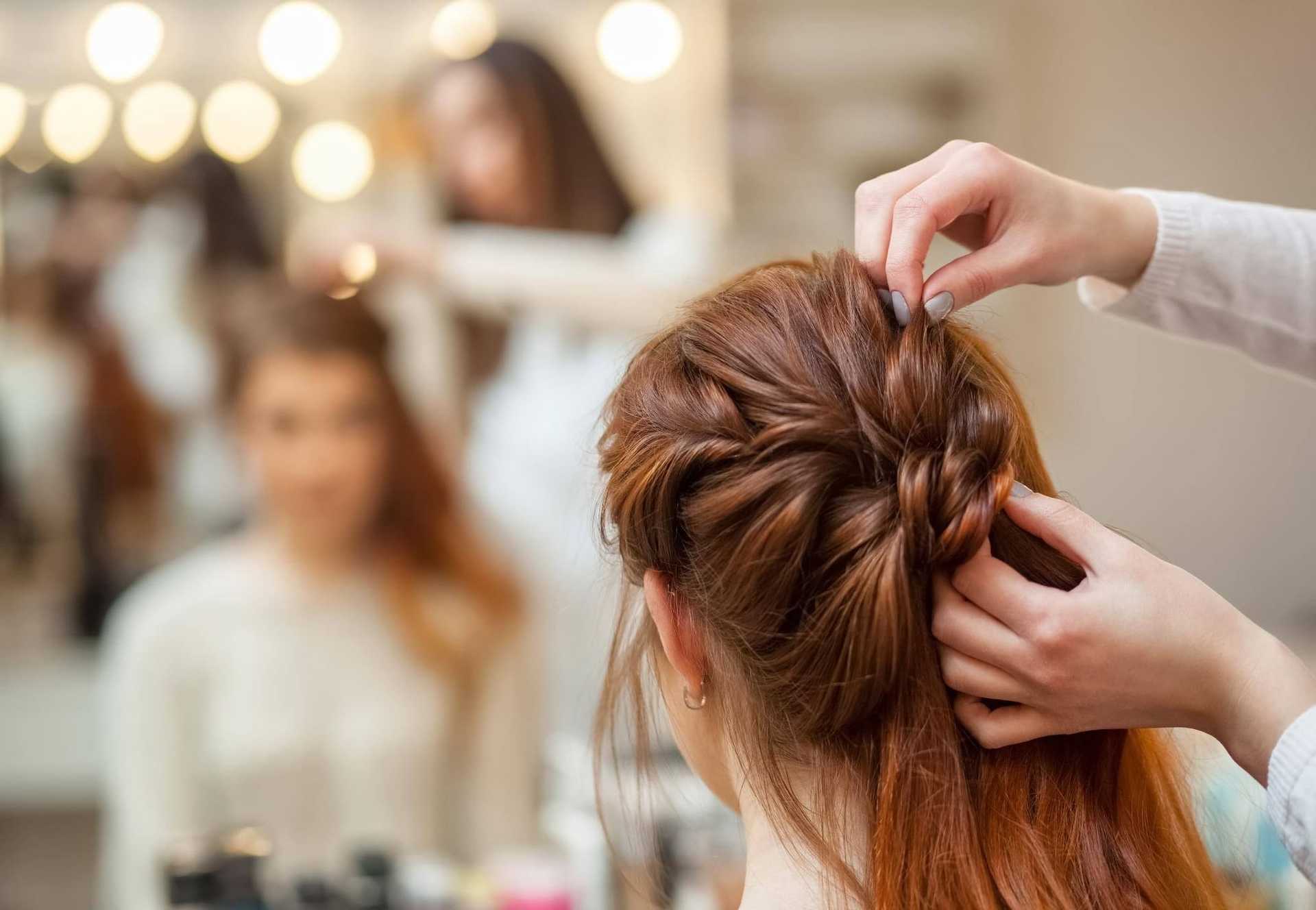 Woman having hair styled in a braid at a salon.