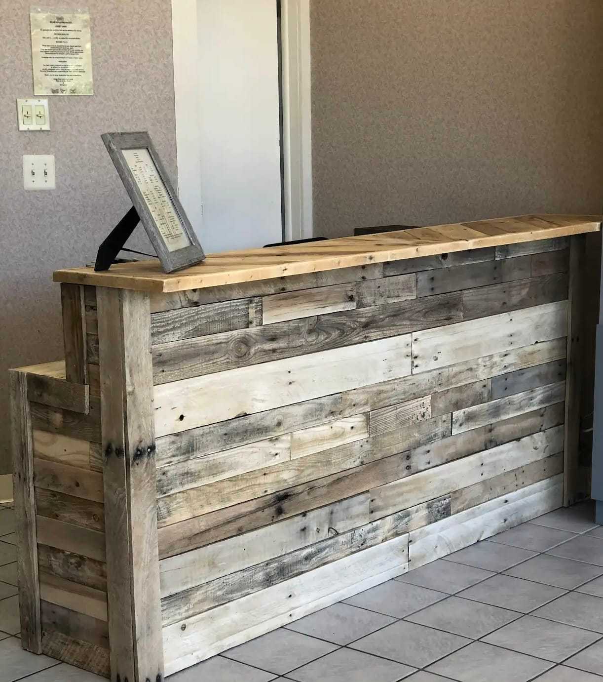 Rustic wooden reception desk in a tiled room with framed document on top.