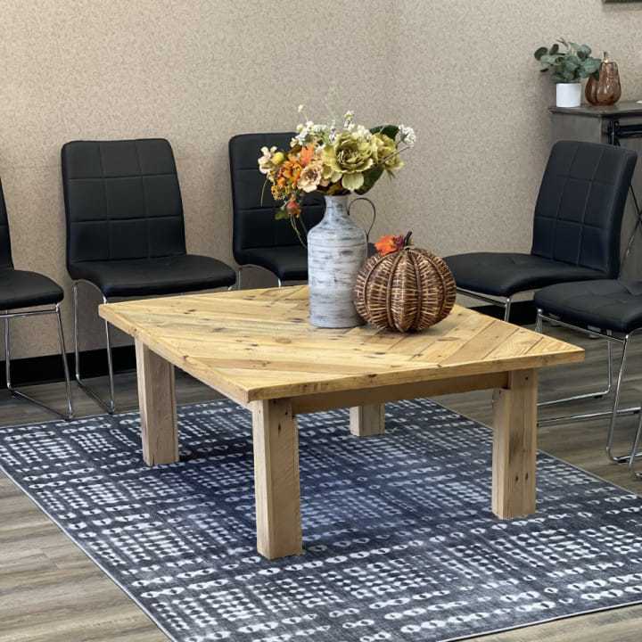 Cozy waiting room with a wooden table, floral vase, and pumpkin decor on a patterned rug.