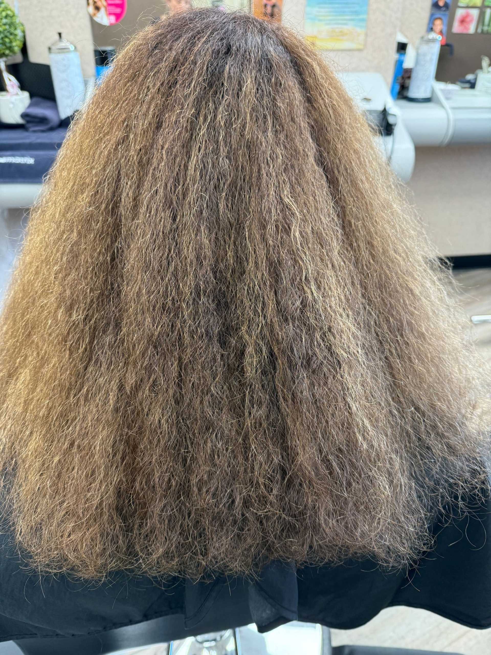 Frizzy, voluminous hair from the back in a salon setting.