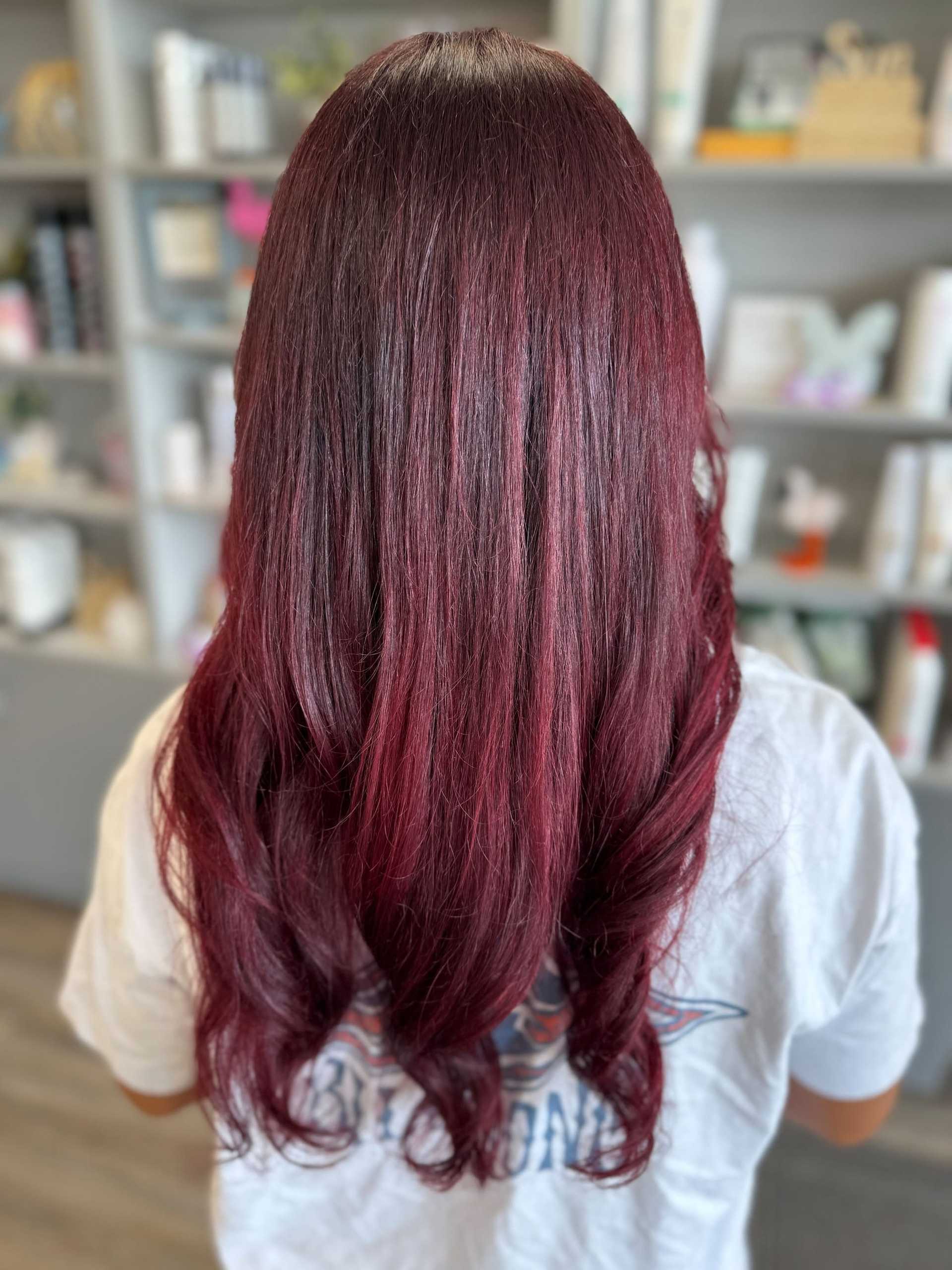 Red ombre hair with soft curls, viewed from the back in a salon setting.